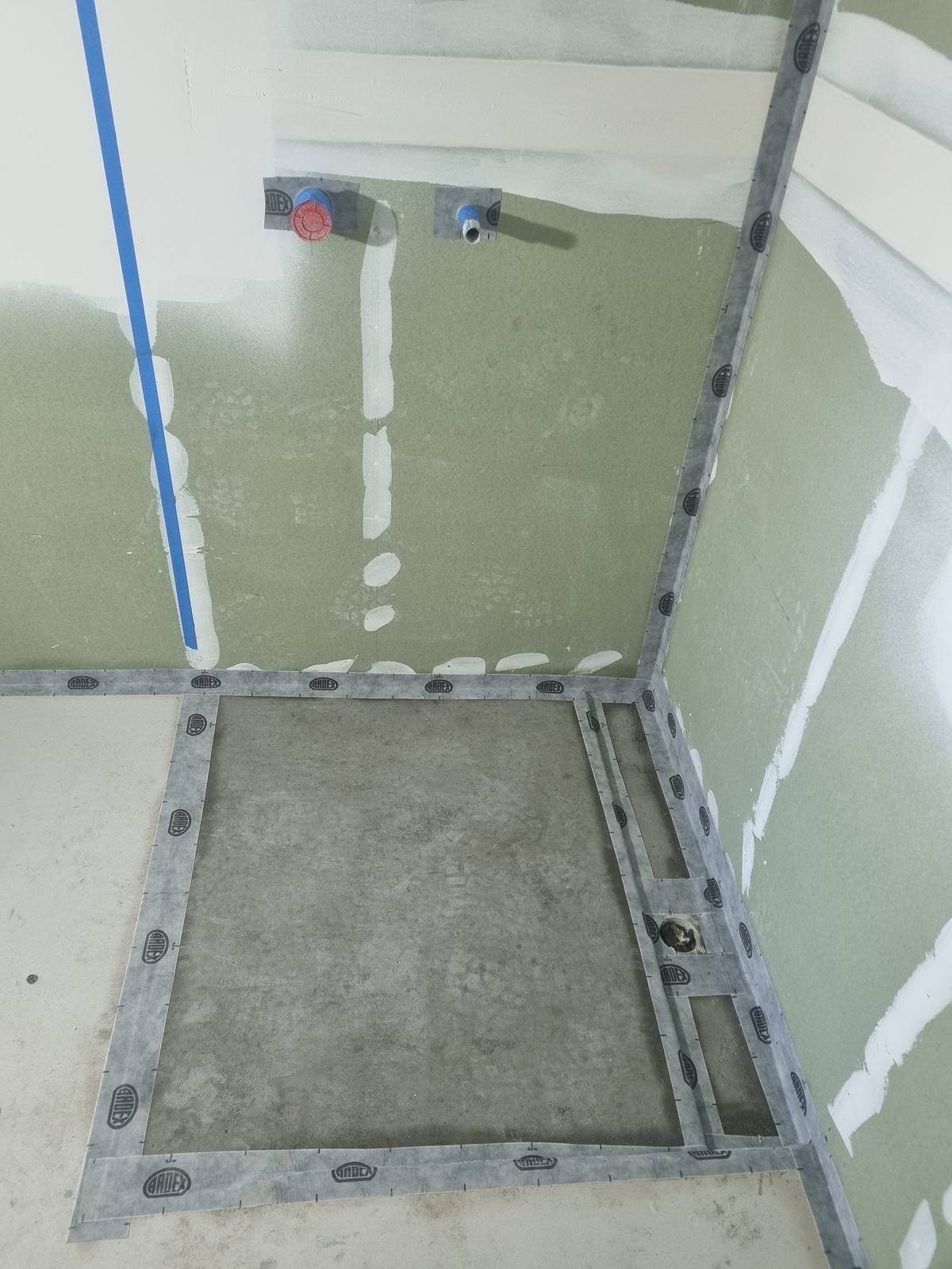 ARDEX tape and pipe collars sealing a shower corner and tap penetrations before waterproofing