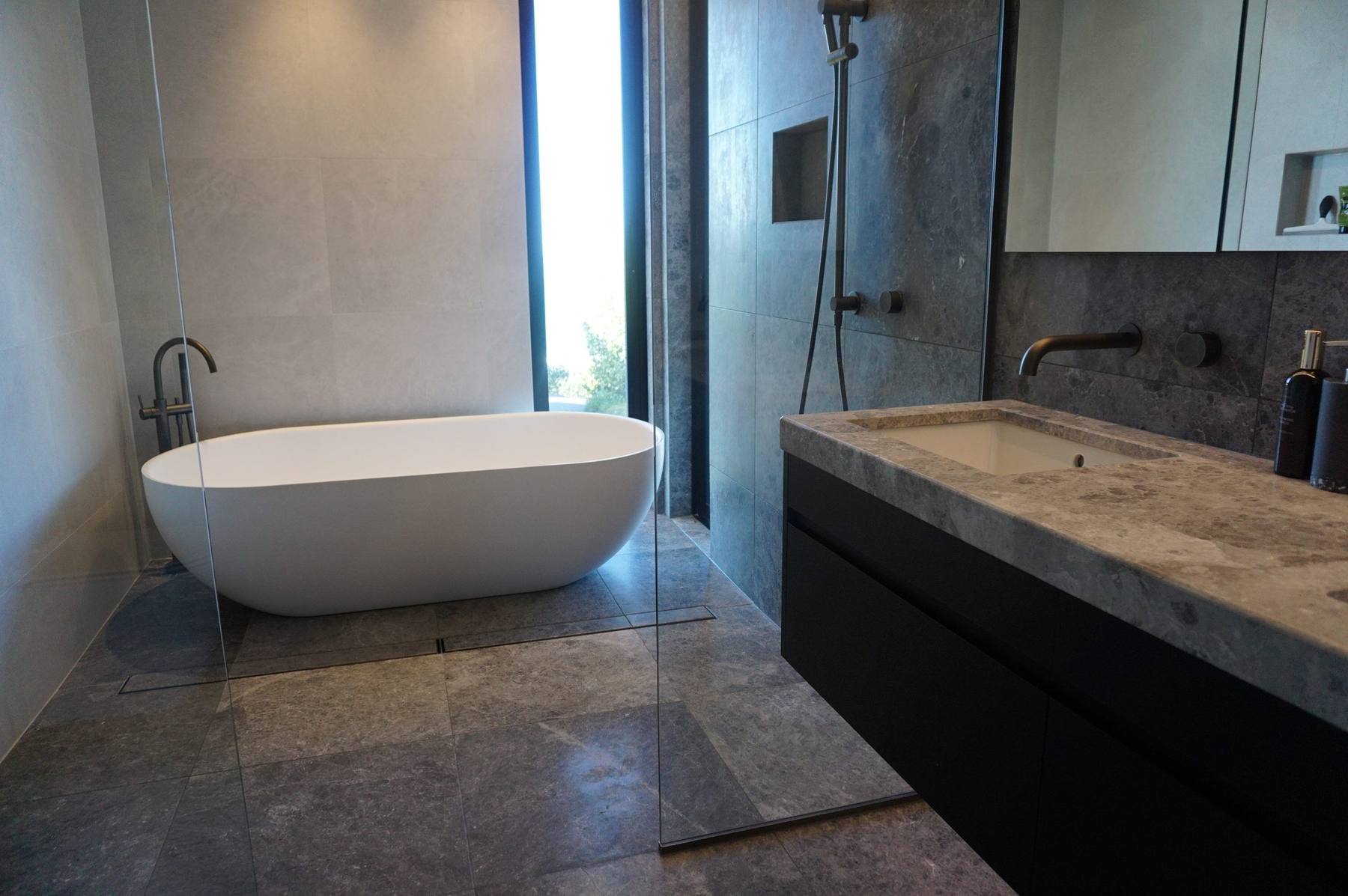 Blue limestone bathroom with freestanding bath, walk-in shower with niche and a stone vanity top, Wainui, Gisborne