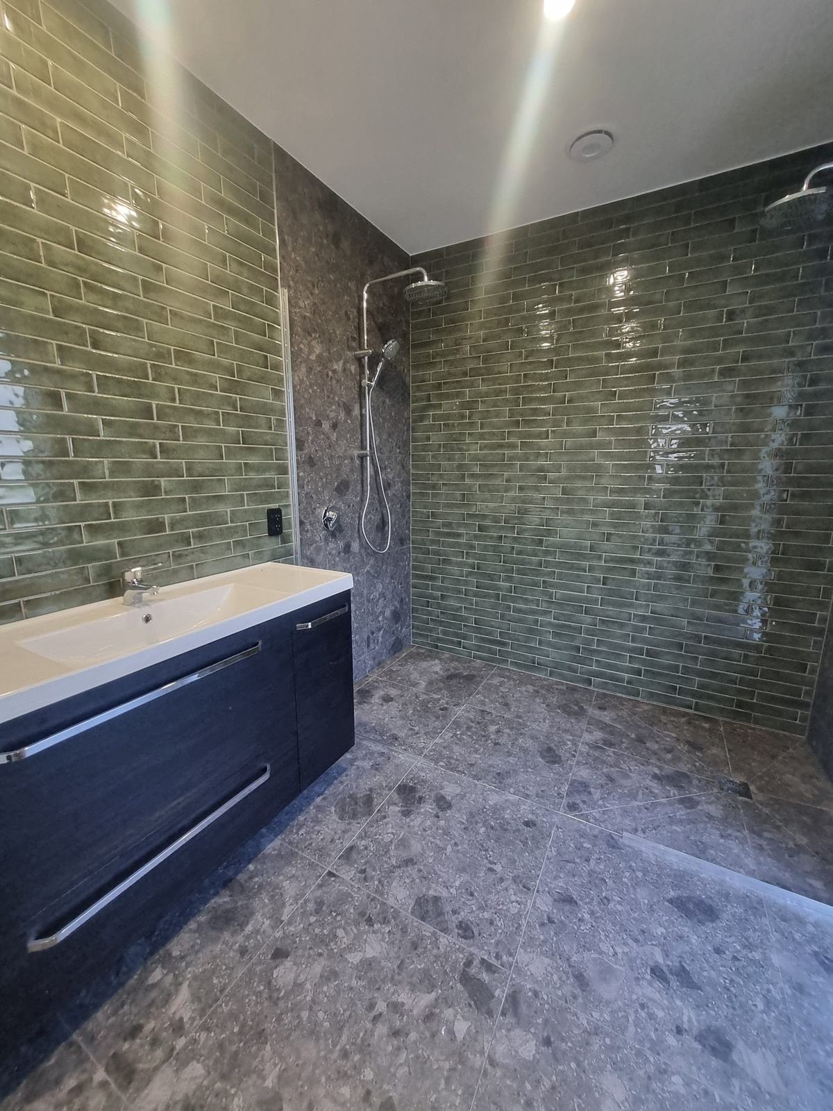 Green subway tile and terrazzo-look walk-in shower