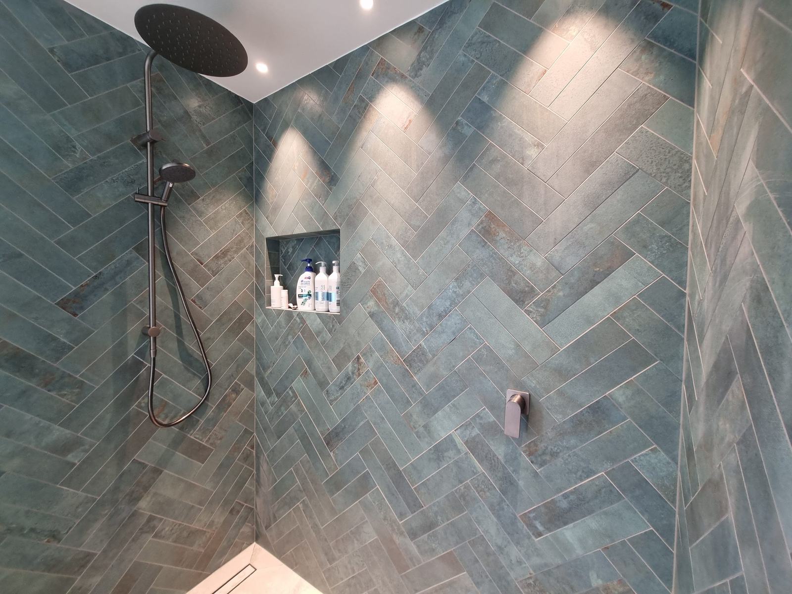 Herringbone-pattern tiled shower with recessed niche
