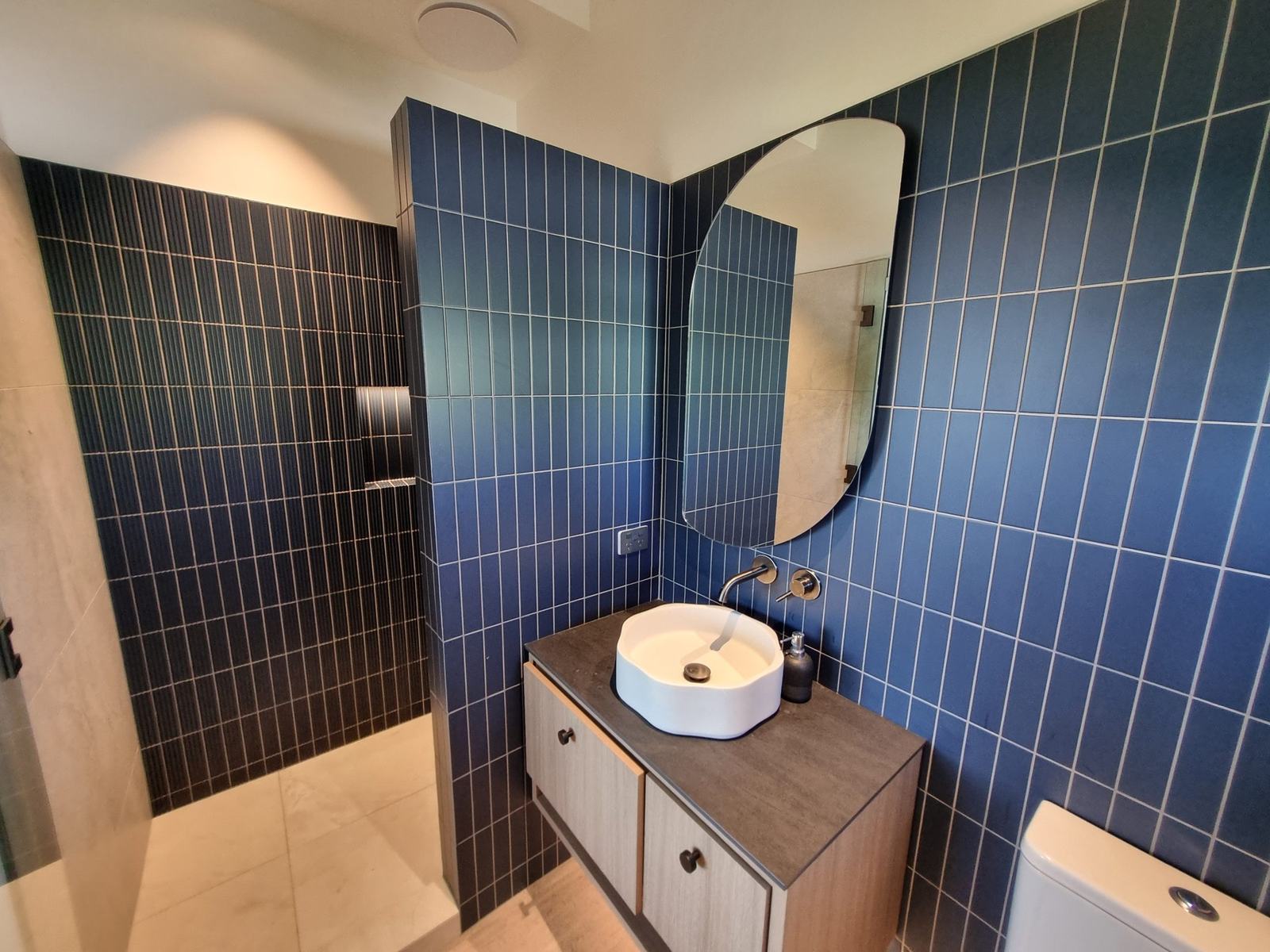 Navy vertical-stack tile bathroom with fluted shower wall