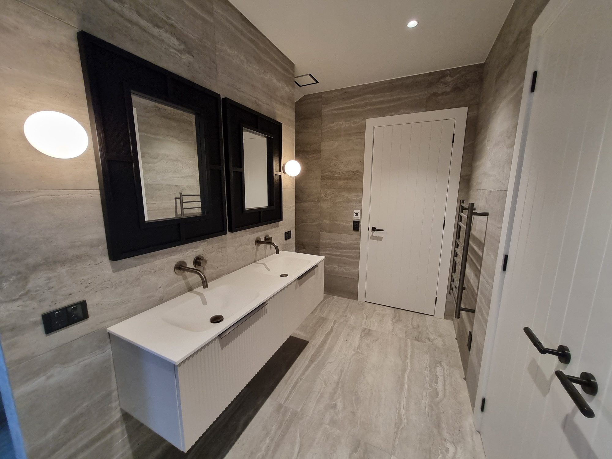 Floating double vanity, black framed mirrors and heated towel rail in the Palmer Mill bathroom, all in large-format tile