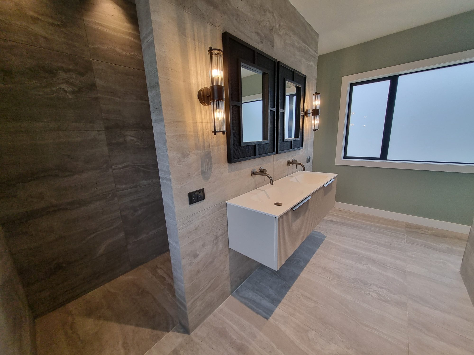 Palmer Mill master ensuite with large-format travertine-look tiles, floating double vanity, black framed mirrors and an open shower
