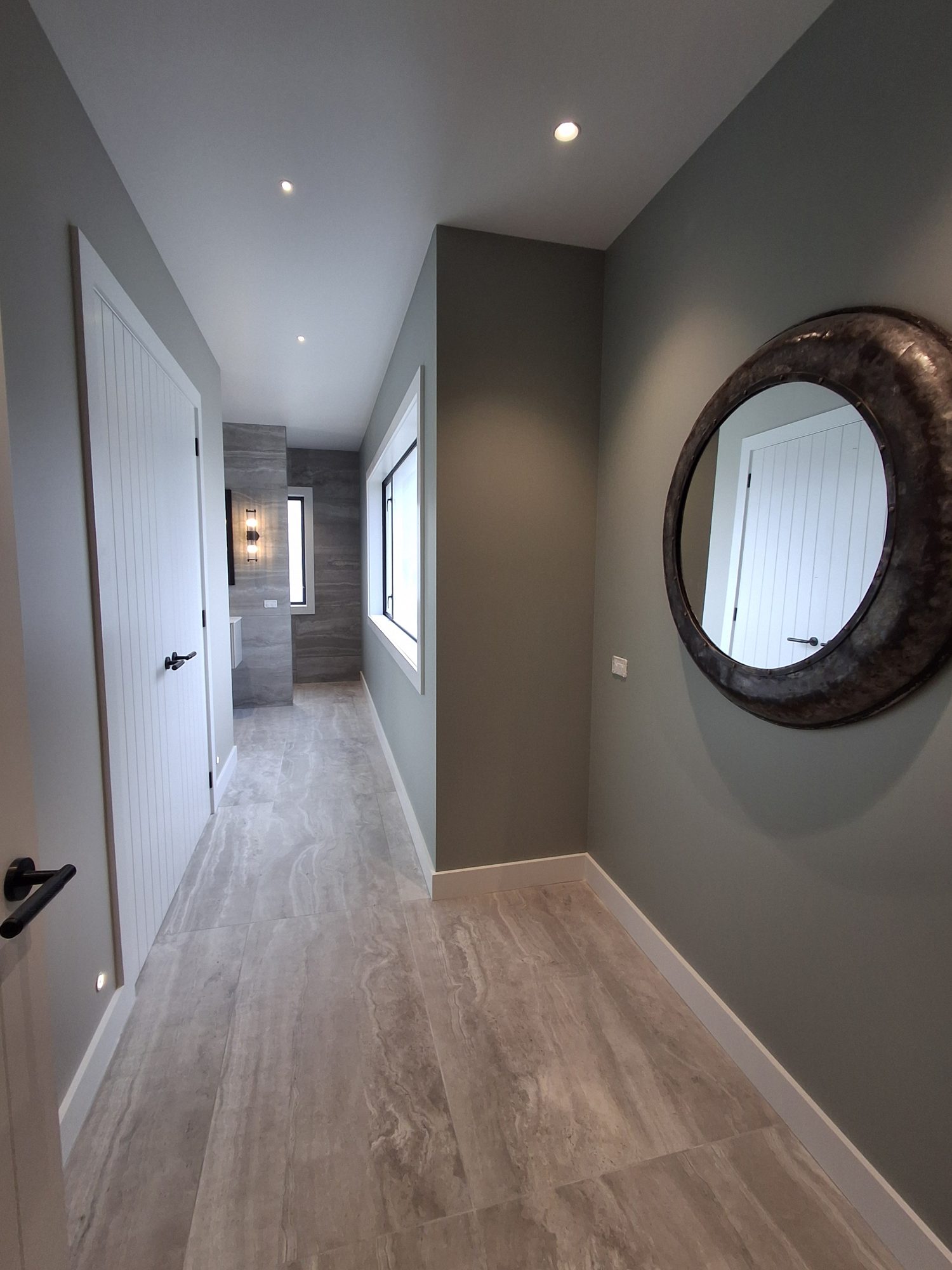 Large-format travertine-look tile floor running down a hallway towards the Palmer Mill master ensuite