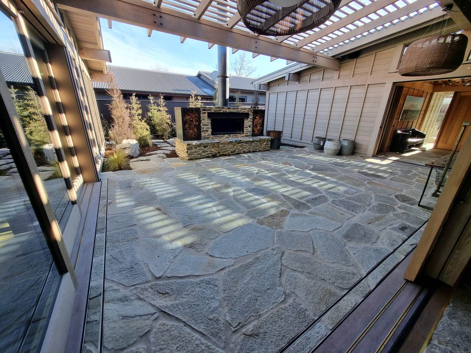 Natural stone crazy paving courtyard with outdoor fireplace under a pergola