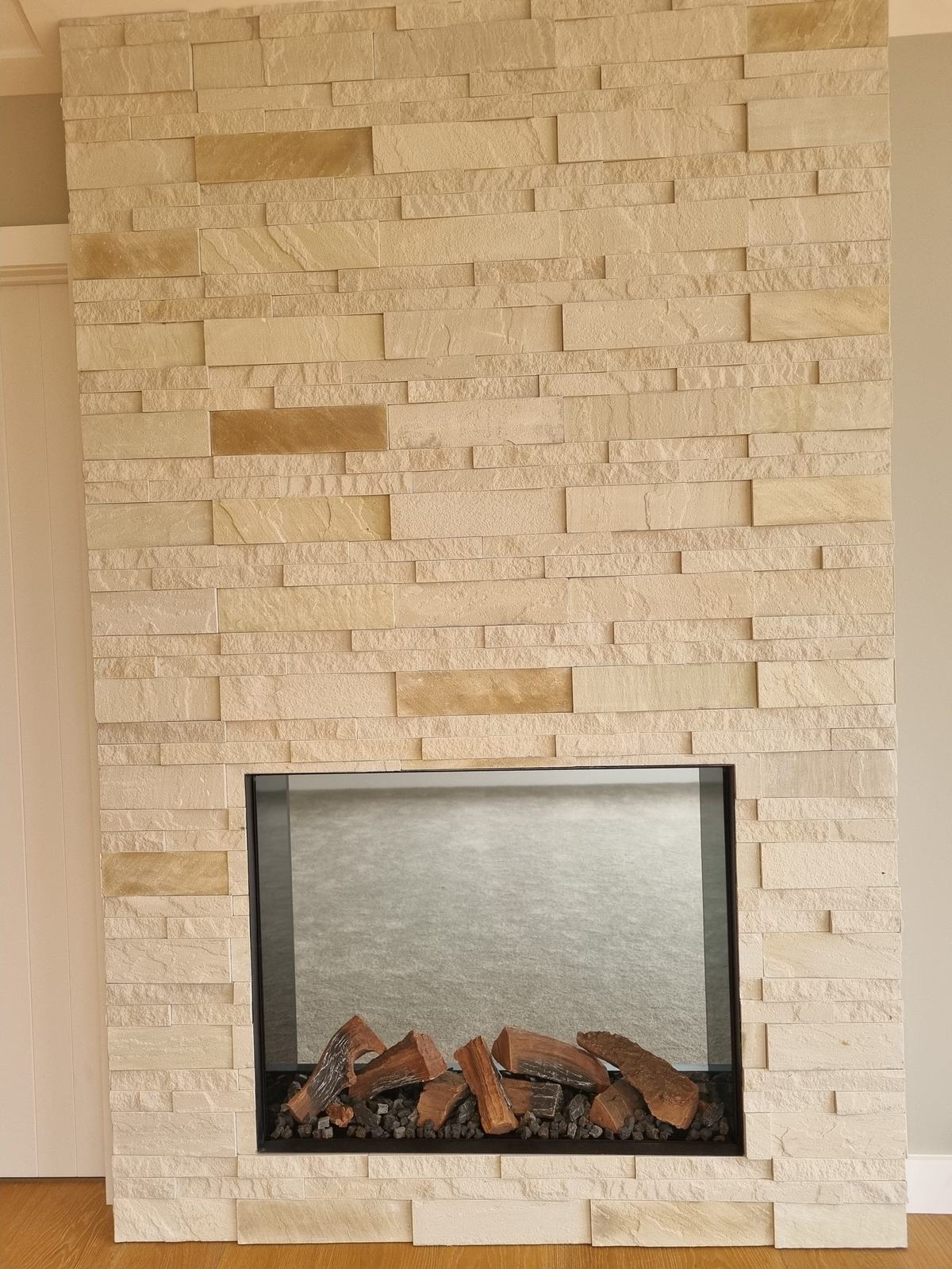 Split face limestone fireplace surround with inset log fire
